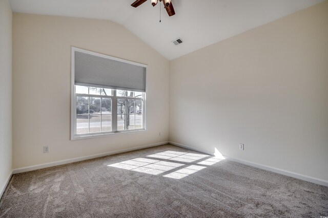 carpeted spare room with visible vents, vaulted ceiling, baseboards, and ceiling fan