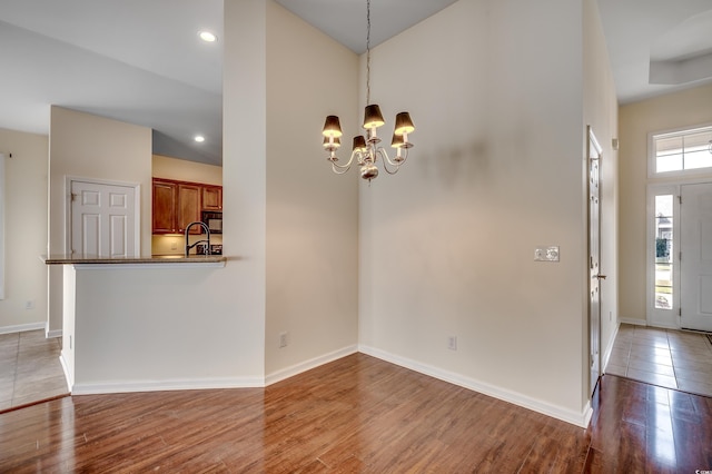 interior space featuring light wood-style flooring, baseboards, a notable chandelier, and recessed lighting