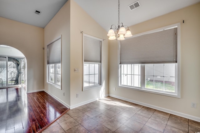 unfurnished dining area featuring lofted ceiling, visible vents, a notable chandelier, and baseboards