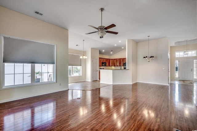 unfurnished living room with ceiling fan with notable chandelier, visible vents, baseboards, and wood finished floors