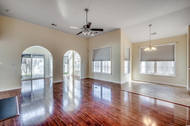 unfurnished living room featuring arched walkways, wood finished floors, visible vents, and a healthy amount of sunlight