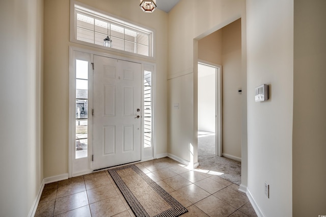 tiled foyer with a high ceiling, plenty of natural light, and baseboards