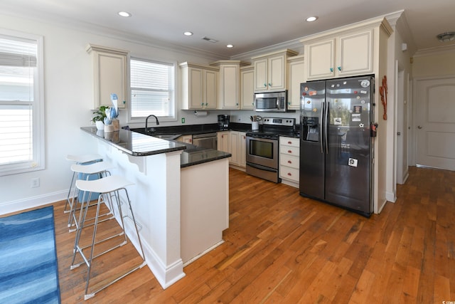 225-B Dogwood Dr N, Murrells Inlet, SC 29576 - kitchen featuring a kitchen bar, ornamental molding, appliances with stainless steel finishes, a peninsula, and a sink