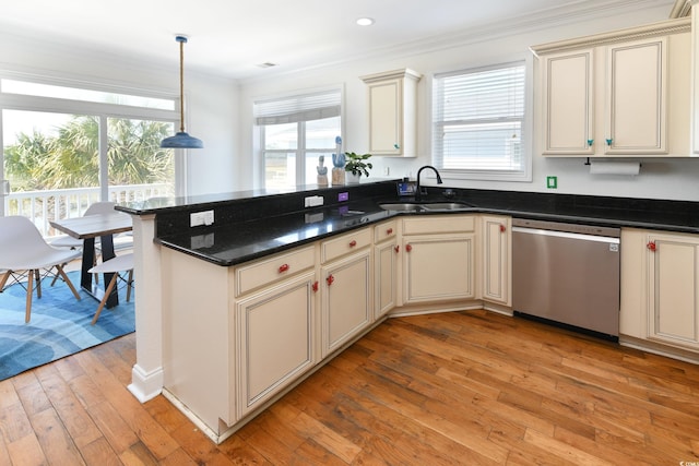 kitchen featuring stainless steel dishwasher, cream cabinets, a sink, and light wood-style floors