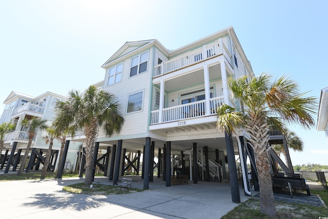 beach home featuring a carport, stairway, and concrete driveway