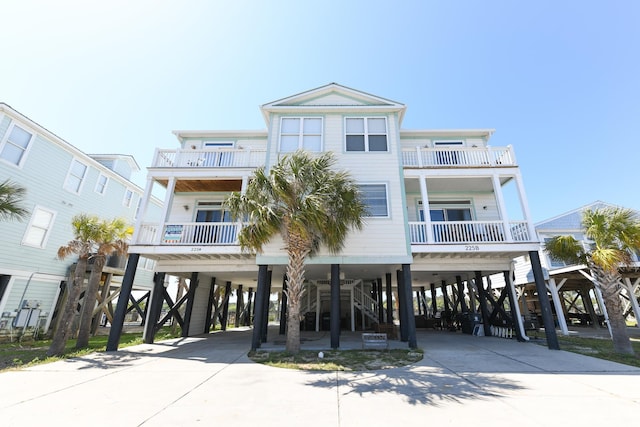 raised beach house featuring a carport, stairway, driveway, and a porch