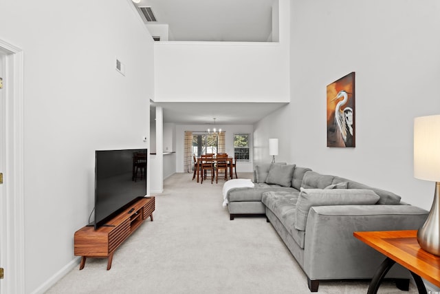 living room with visible vents, light carpet, a high ceiling, and an inviting chandelier