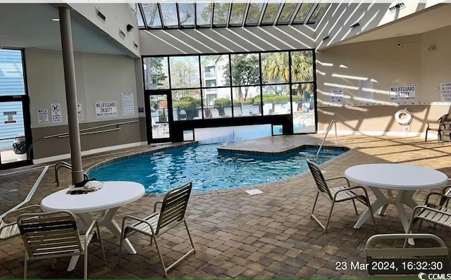 community pool with glass enclosure and a patio