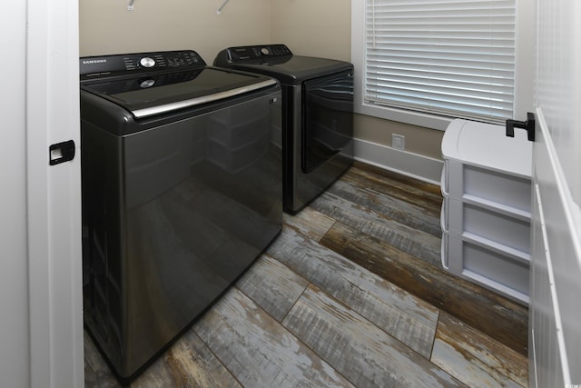 clothes washing area with dark wood finished floors, laundry area, baseboards, and independent washer and dryer