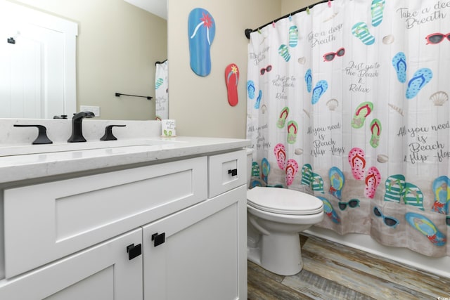 bathroom featuring vanity, toilet, wood finished floors, and shower / bath combo with shower curtain