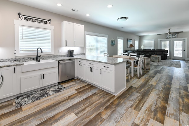 kitchen with a wealth of natural light, dishwasher, a peninsula, and white cabinetry