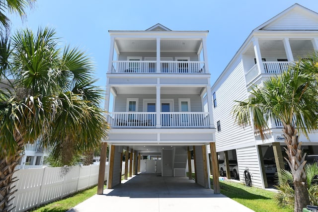 raised beach house featuring a carport, driveway, and fence