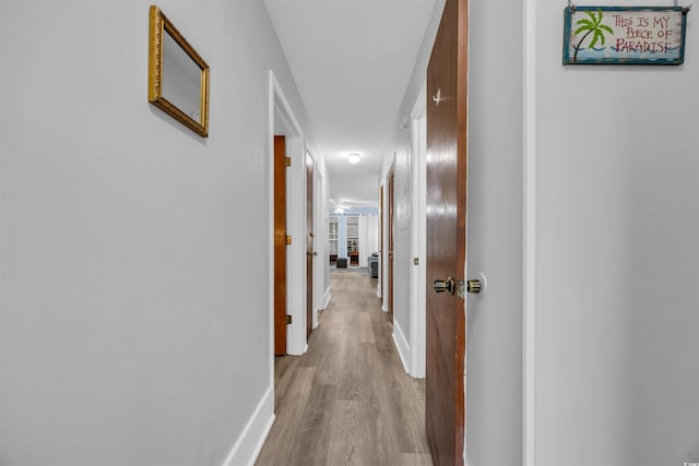 corridor with baseboards and wood finished floors