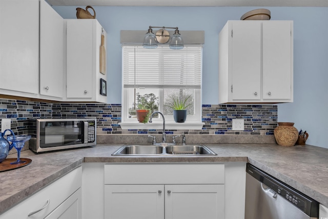 kitchen with a sink, light countertops, white cabinets, backsplash, and appliances with stainless steel finishes