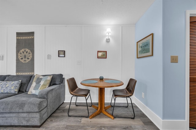 dining space with a textured ceiling, wood finished floors, and baseboards