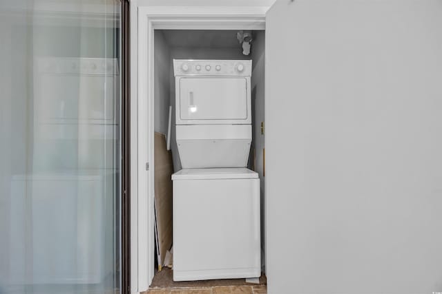 clothes washing area featuring stacked washer and clothes dryer and laundry area