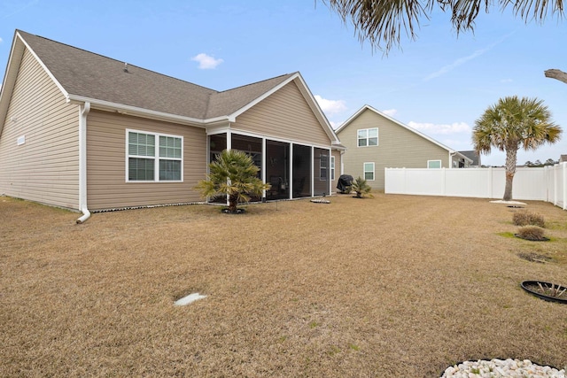 rear view of house with a yard, a sunroom, a shingled roof, and fence