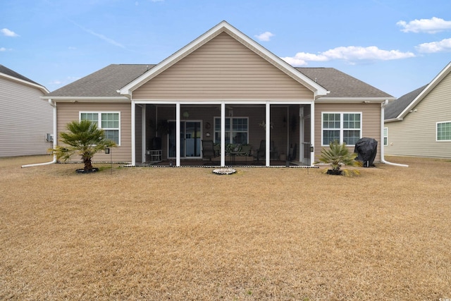 back of house featuring a lawn, roof with shingles, and a sunroom