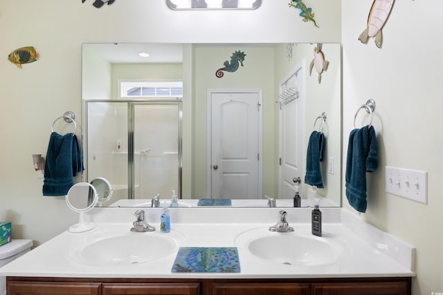 bathroom with double vanity, toilet, a stall shower, and a sink