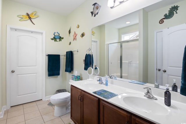 bathroom featuring tile patterned flooring, double vanity, a stall shower, and a sink