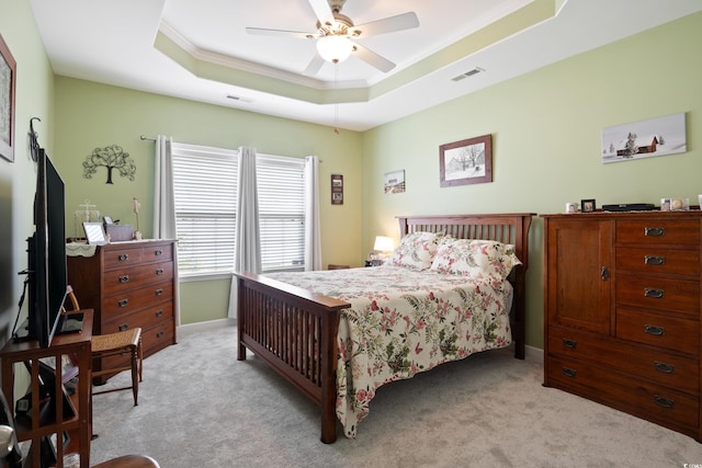 bedroom featuring a ceiling fan, visible vents, a tray ceiling, light carpet, and crown molding