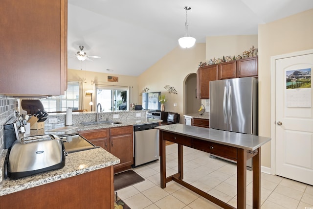 kitchen with light tile patterned floors, appliances with stainless steel finishes, arched walkways, and a sink