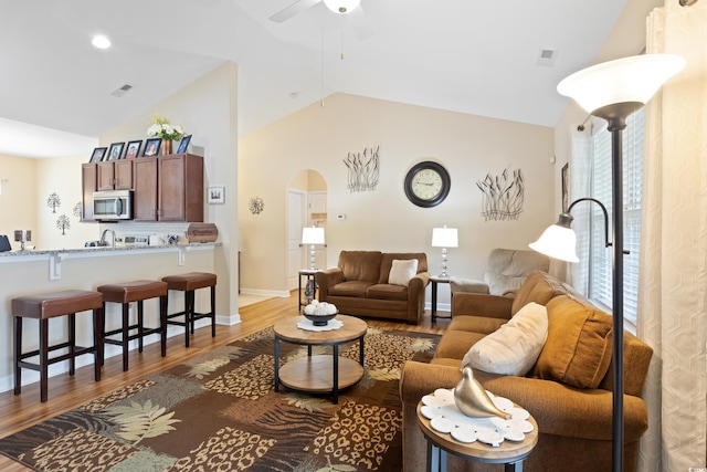 living area featuring a ceiling fan, visible vents, wood finished floors, and arched walkways