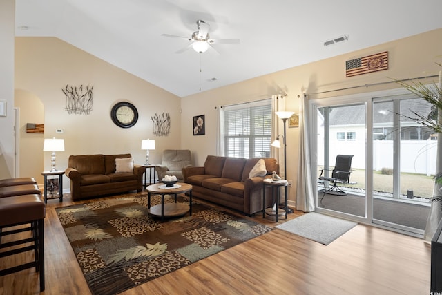 living area with visible vents, a ceiling fan, wood finished floors, arched walkways, and vaulted ceiling