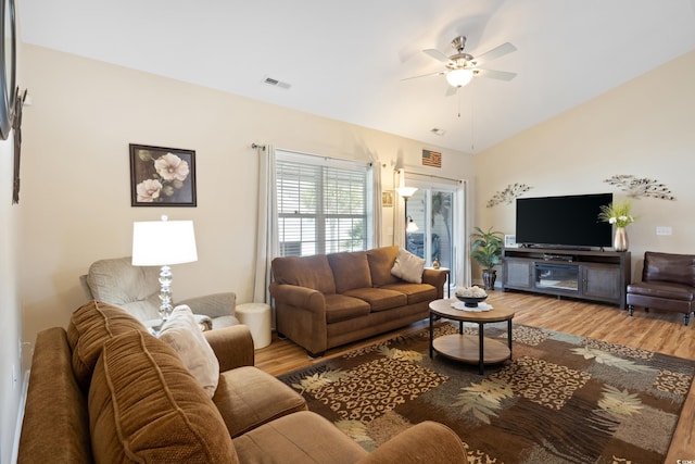 living area with visible vents, lofted ceiling, wood finished floors, and a ceiling fan