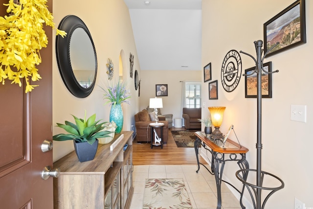 hallway featuring vaulted ceiling and light tile patterned floors