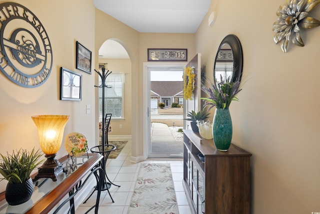 foyer featuring light tile patterned floors, baseboards, and arched walkways