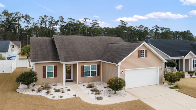 view of front of house with roof with shingles, concrete driveway, and fence