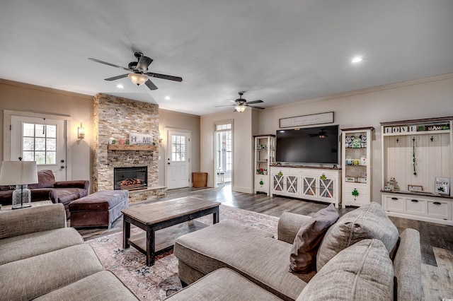 living area featuring recessed lighting, ornamental molding, wood finished floors, and a stone fireplace