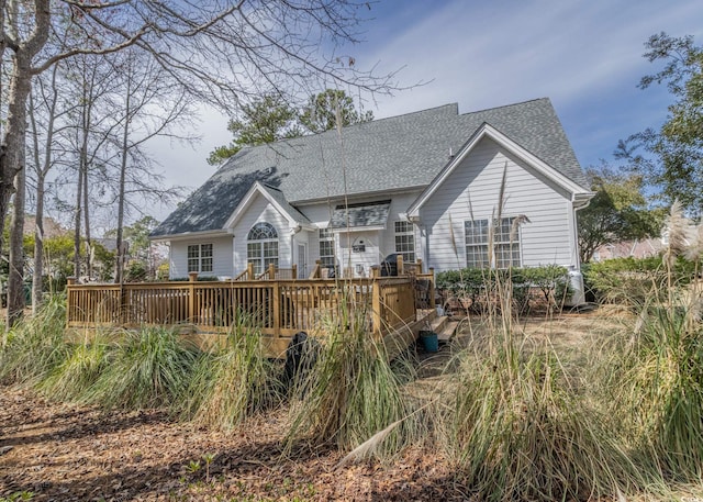 rear view of house featuring roof with shingles and a wooden deck