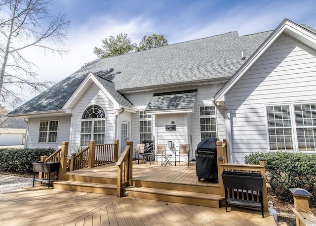 rear view of house featuring a deck and roof with shingles