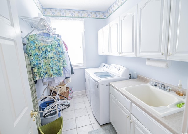 clothes washing area featuring cabinet space, light tile patterned floors, baseboards, washing machine and clothes dryer, and a sink