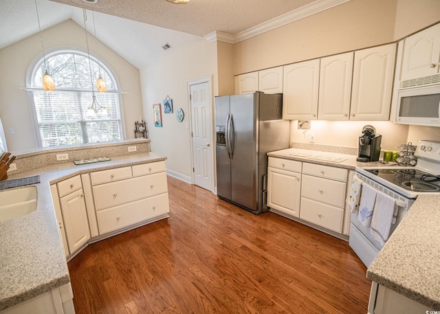 kitchen featuring white appliances, wood finished floors, vaulted ceiling, pendant lighting, and a sink