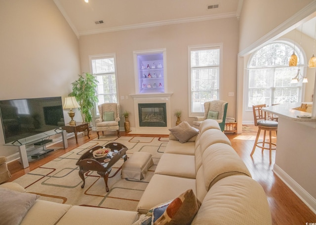 living room with wood finished floors, a glass covered fireplace, visible vents, and a healthy amount of sunlight