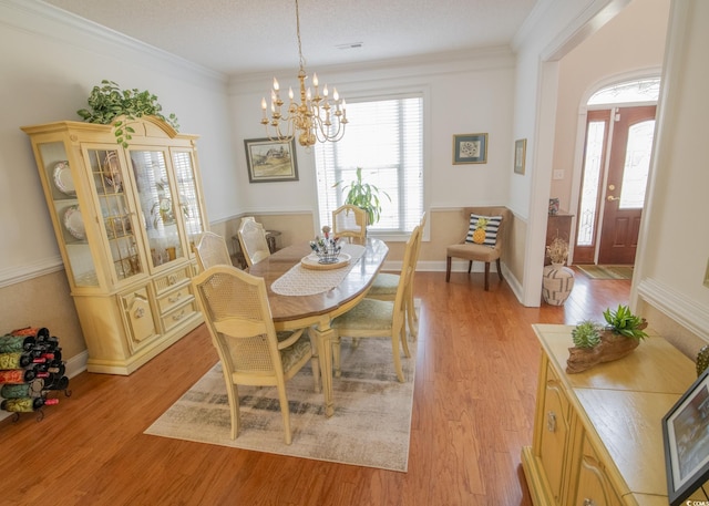 dining room featuring crown molding, visible vents, light wood-style flooring, a chandelier, and baseboards