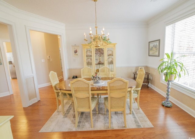 dining room featuring a notable chandelier, light wood-style flooring, and crown molding