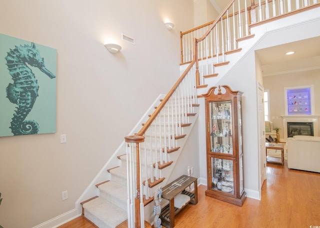 staircase featuring wood finished floors, visible vents, and baseboards