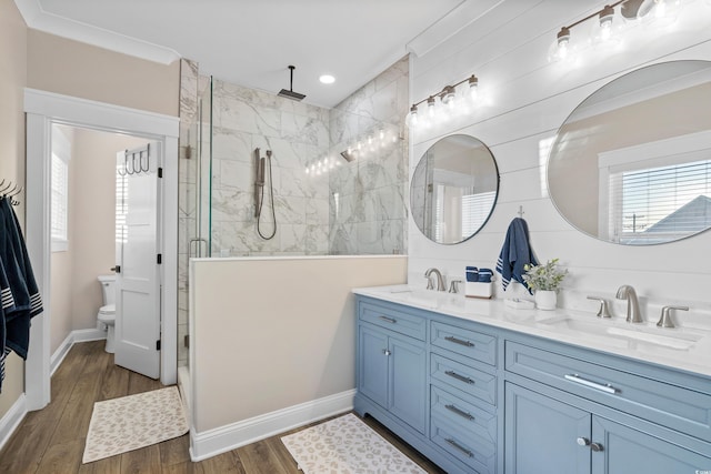 bathroom with double vanity, wood finished floors, a stall shower, and a sink