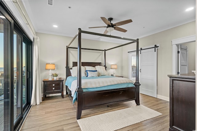 bedroom featuring ornamental molding, light wood-type flooring, baseboards, and a barn door