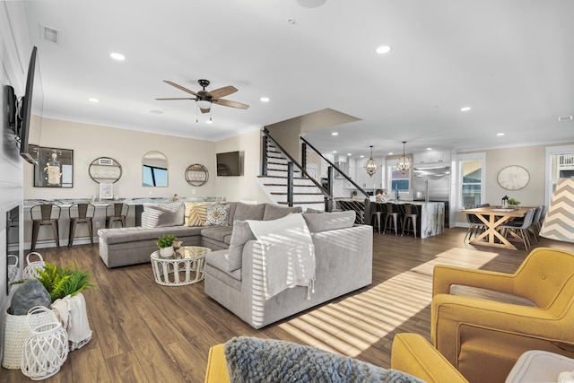 living area featuring stairway, visible vents, wood finished floors, and ornamental molding