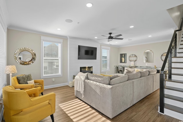 living area with stairs, ornamental molding, a fireplace, and wood finished floors