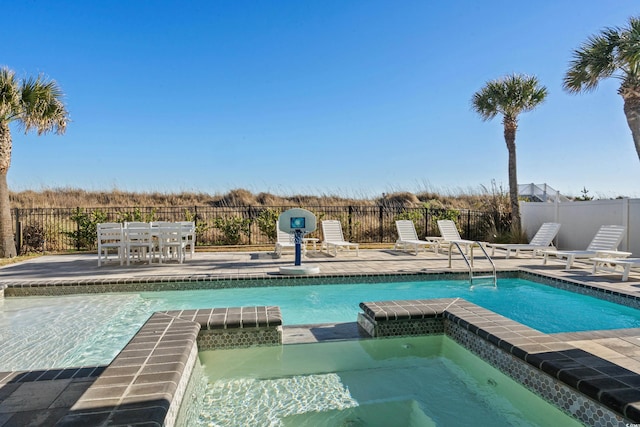 view of pool with a patio area, fence, and a pool with connected hot tub