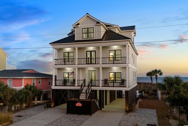 beach home featuring a porch, a balcony, stairway, board and batten siding, and a standing seam roof