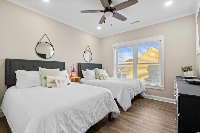 bedroom with dark wood-style floors, visible vents, crown molding, and baseboards