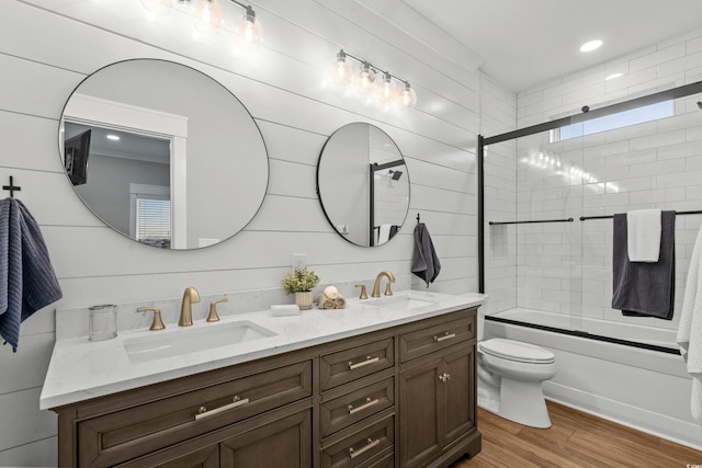 full bath featuring double vanity, a sink, toilet, and wood finished floors