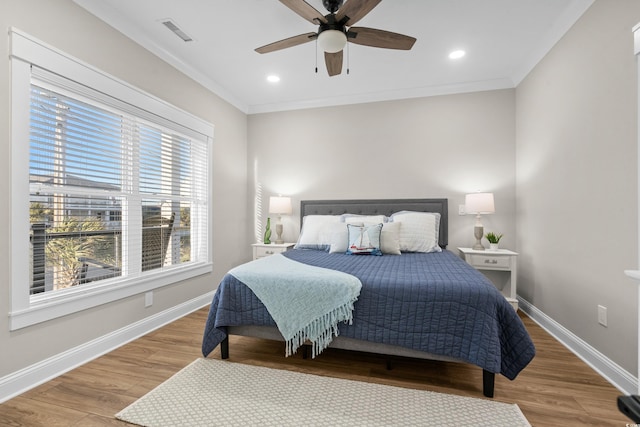 bedroom featuring ornamental molding, wood finished floors, visible vents, and baseboards